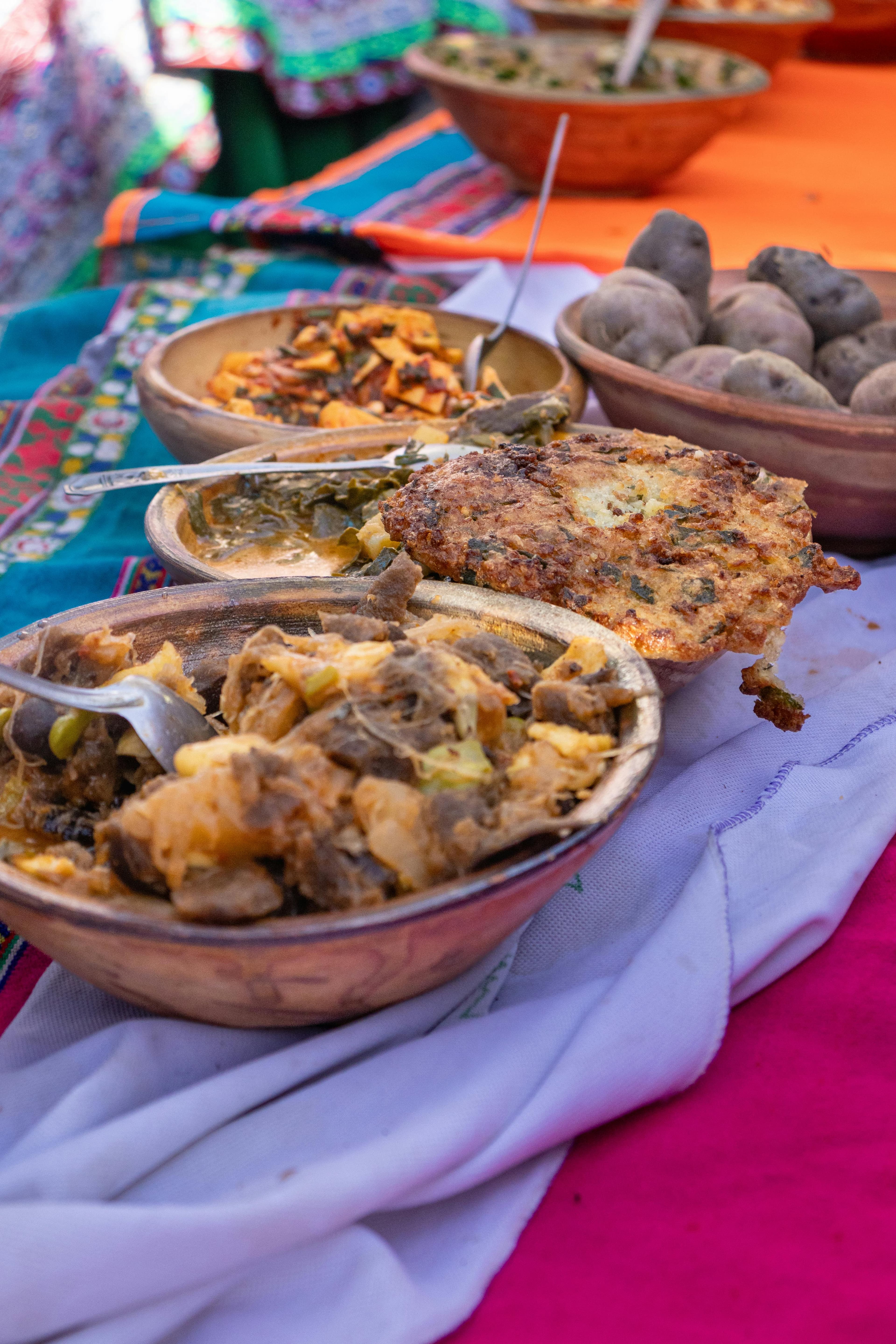 Family-style bowls of stews and sides on a colorful table