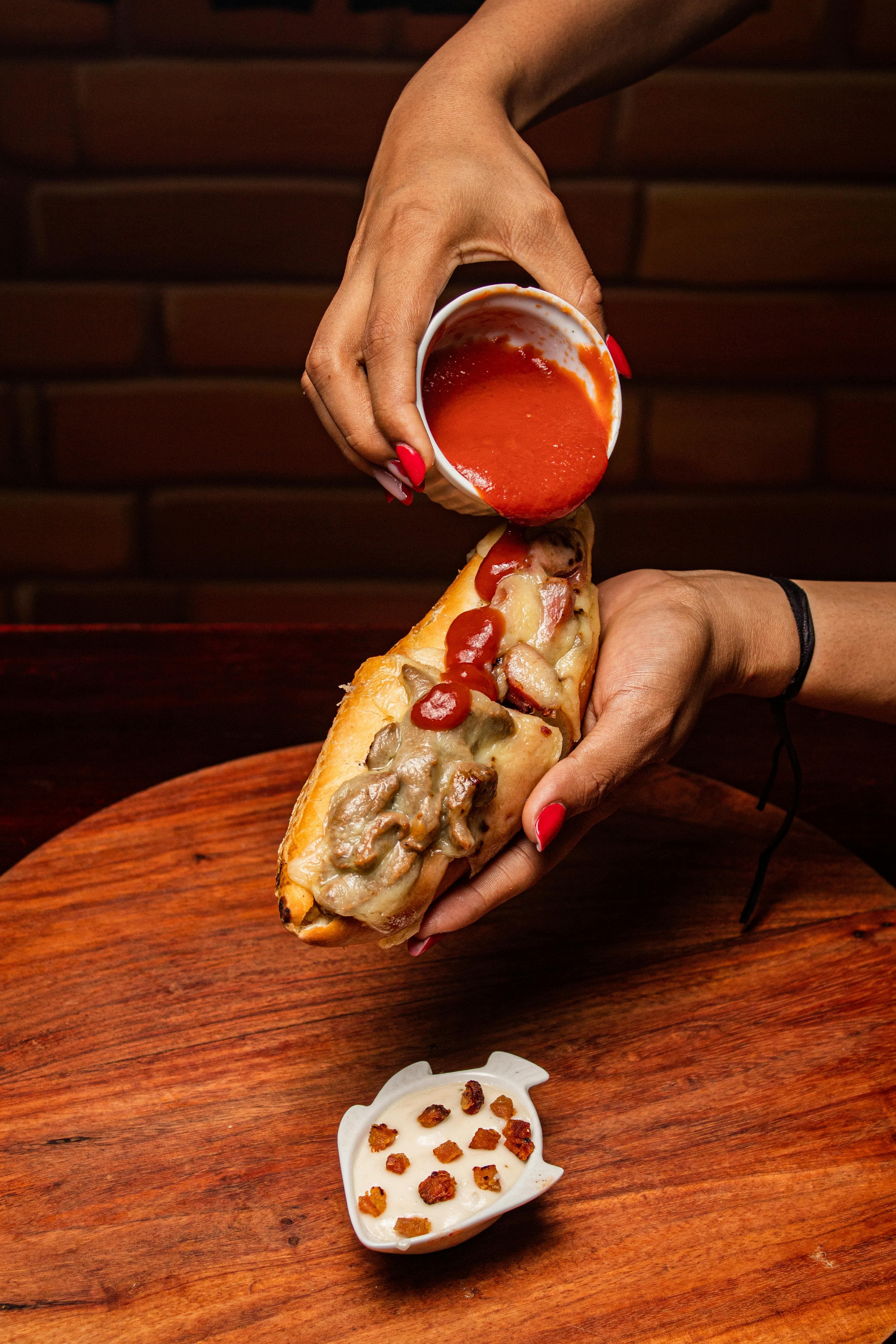 A loaded cheesesteak being drizzled with sauce
