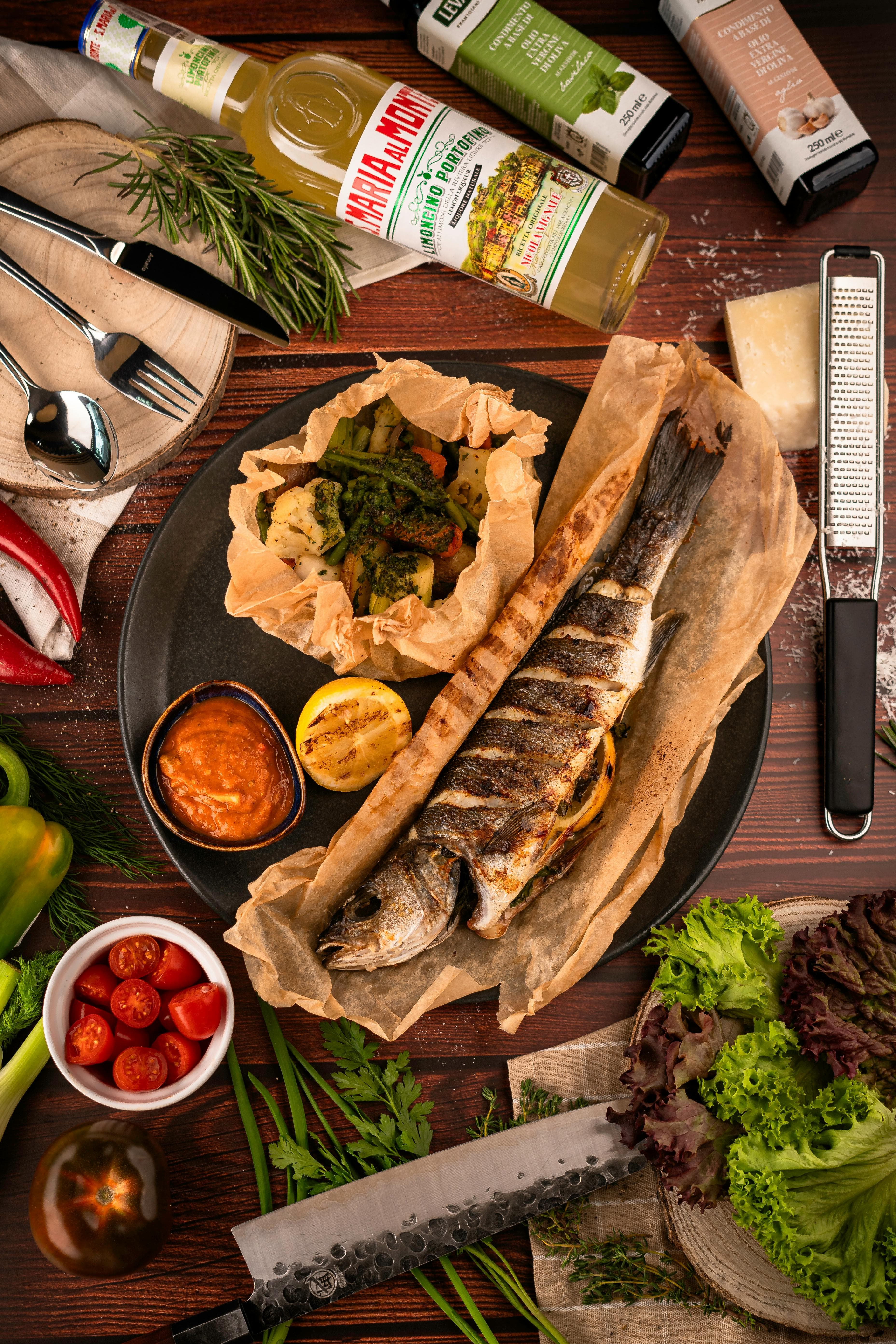 Whole grilled fish plated with herbs, vegetables, and sides